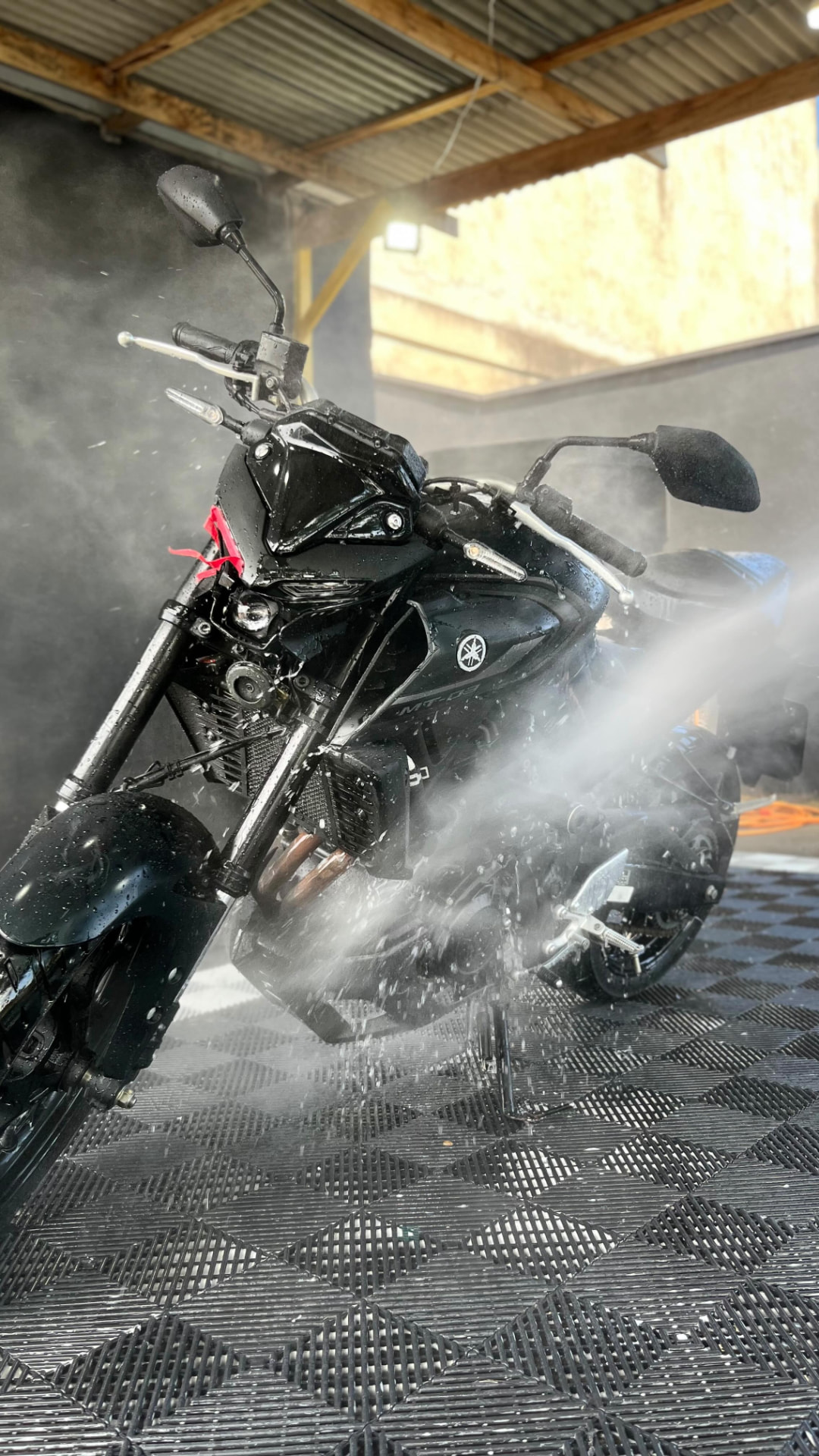 Moto esportiva preta sendo lavada com alta pressão